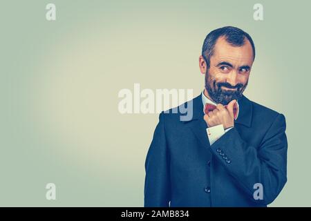 Ritratto sly bearded uomo affare creatore che plotting qualcosa, nascondendo una carta nascosta dell'asso nella manica della giacca della tuta, guardando scettico pensieroso a fronte di coys laterali Foto Stock