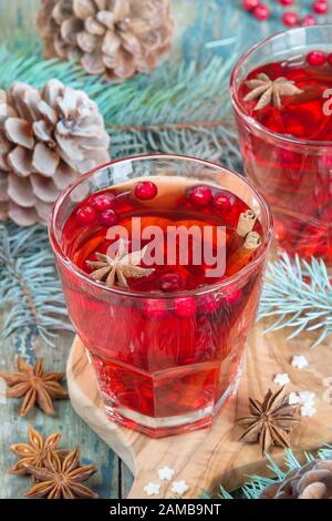 Tavolo di Natale - due bicchieri di vino rosso caldo mulled con spezie e cowberries circondato da rami di abete e coni Foto Stock