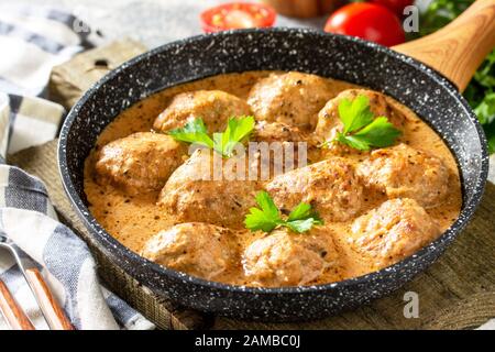 Polpette in panna acida e salsa di pomodoro in una padella su un tavolo di pietra. Foto Stock