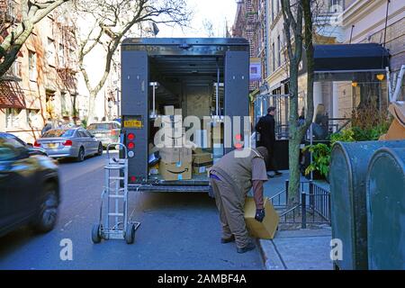 New YORK, NY -9 GENNAIO 2020 - Vista di un operaio UPS davanti al suo camion a consegna aperta che trasporta le scatole pesanti Amazon.com sulla strada del Greenwich Village, Foto Stock