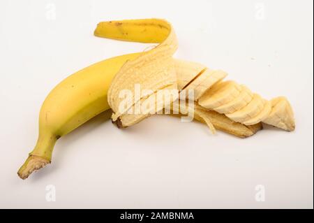 Un giallo maturo parzialmente sbucciato e tagliato in parecchie parti banana su uno sfondo bianco. Primo piano Foto Stock