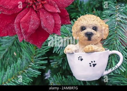 Figurina ceramica di un piccolo cucciolo seduto in una tazza bianca. Foto Stock