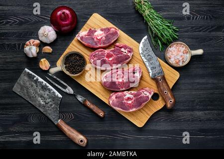 Vista dall'alto dello stinco di agnello fresco tritato sul tagliere con spezie Foto Stock