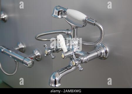 rubinetto in acciaio cromato e porcellana su sfondo grigio Foto Stock