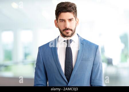 Ritratto di giovane sales man con faccia seria in piedi in ufficio. Foto Stock
