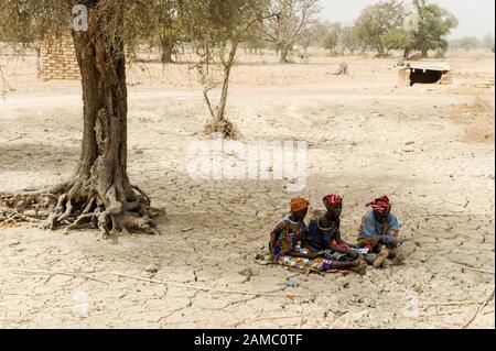 Burkina FASO, villaggio SAMBOAGA, siccità, donne seduta su campo secco con terreno incrinato Foto Stock