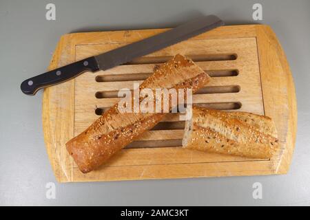 Pezzi di pane tradizionale francese baguette e coltello su un tagliere Foto Stock