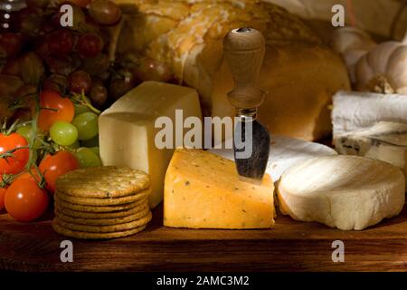 Tagliere di formaggio con formaggi assortiti frutta e verdura Foto Stock