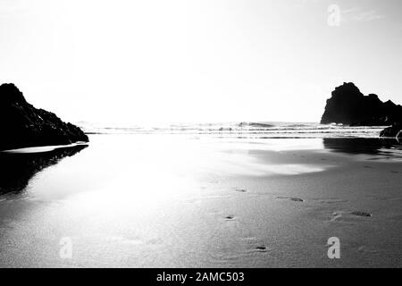 Impronte sulla spiaggia a Kynance Cove, Cornovaglia, in bianco e nero con contrasto elevato Foto Stock