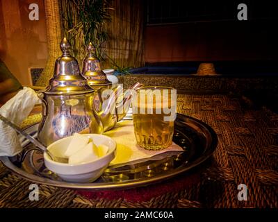 Tè alla menta fresco in pentole e vasetti tipici di metallo da tè in un ristorante, Marrakech, Marocco. Si tratta di un tipico tè berbero, chiamato anche berbero whiskey. Foto Stock