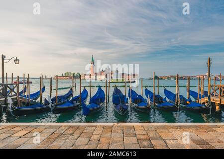 Venezia, Italia. Molo con gondole ormeggiate su Piazza San Marco con la chiesa di San Giorgio di maggiore sullo sfondo durante l'alba Foto Stock