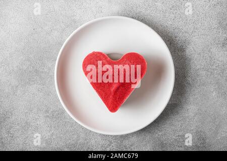 Dessert di San Valentino. Torta vegana cruda a forma di cuore in un piatto. Cibo sano e delizioso. Vista dall'alto. Concetto di amore Foto Stock