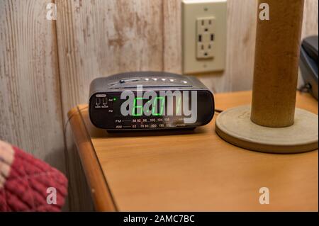 Comodino con lampada da tavolo, sveglia e telefono a toni Foto Stock