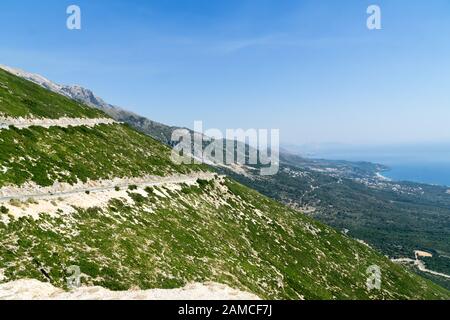Una strada tortuosa per il Passo di Llogara vicino a Dhermi con una magnifica vista della Riviera Albanese, cielo blu e mare turchese. Albania, Europa. Foto Stock