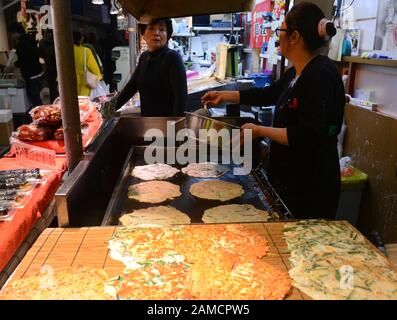 Bancarelle di cibo che vendono pancake salati coreani nel vivace mercato alimentare di Tsuruhashi, Osaka. Foto Stock