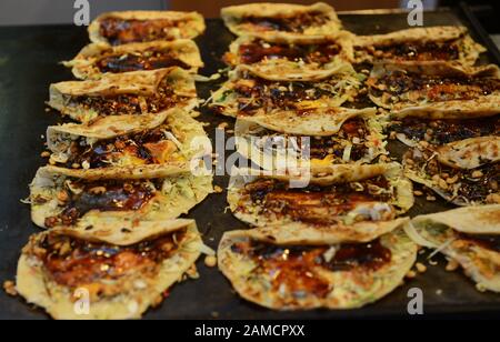 Bancarelle di cibo che vendono pancake salati coreani nel vivace mercato alimentare di Tsuruhashi, Osaka. Foto Stock