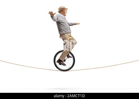 Un uomo anziano che guida un monociclo su una corda isolata su sfondo bianco Foto Stock