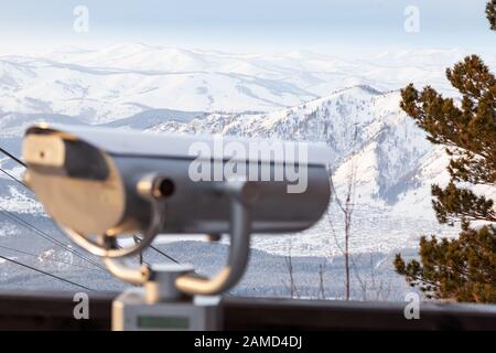 Binocolo fisso sulla piattaforma di osservazione sulle montagne Altai in inverno con neve e uno splendido paesaggio. Riposo e viaggi durante le vacanze wi Foto Stock