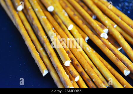 Cannucce saporite e salate con sale fatto di farina, sneking sparse su uno sfondo di plastica nera. Foto Stock