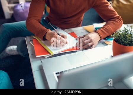 Studente che scrive nel suo notebook mentre si prepara per l'esame Foto Stock