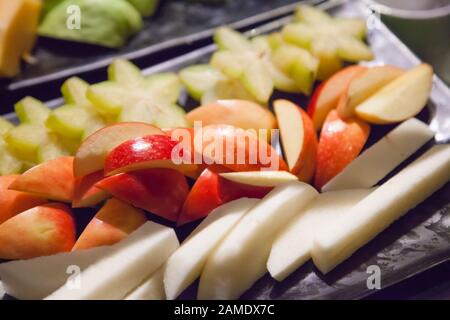 Frutta fresca e assortita di stagione tropicale asiatica (mela, frutta di stellato, yam o jicama) in vassoio nero. Cibo vegetariano e vegano, naturale e Biologico Foto Stock