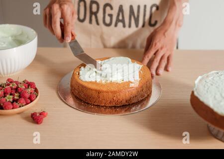 L'uomo pasticcere mettere ciliegina la crema sul pan di spagna. Rendendo pan di spagna serie Foto Stock