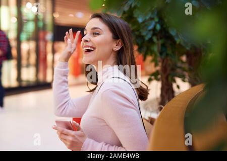 Bella donna che dice ciao e sventolando la sua mano Foto Stock