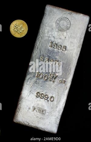 1985 Homestake Mining Company 100.97 oncia troy silver bullion bar versata al piombo, Dakota del Sud - STATI UNITI D'AMERICA. Uno oncia d'oro round mostrato per la scala Foto Stock