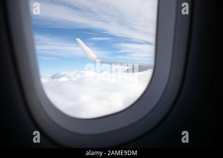 Ala di aeroplano sopra le nuvole vista dalla sua cabina Foto Stock