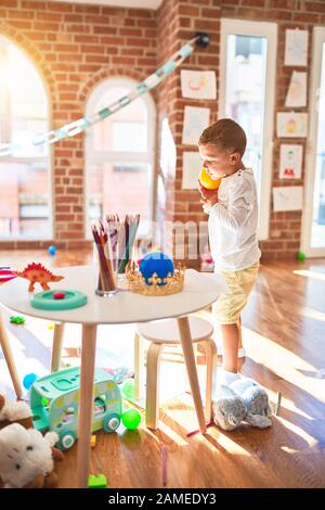 Bella bionda toddler giocando in plastica con cibi e piatti. Piedi intorno un sacco di giocattoli a kindergarten Foto Stock