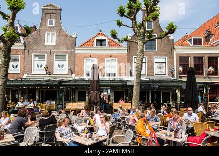 Haarlem, Paesi Bassi - 28 maggio 2019: La gente gusta un drink ai tavoli di bar e ristoranti nella città vecchia di Haarlem con la sua famosa architettura olandese Foto Stock