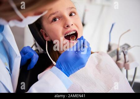 Parte dell'ortodontista che esamina i denti del bambino nell'ufficio del dentista Foto Stock