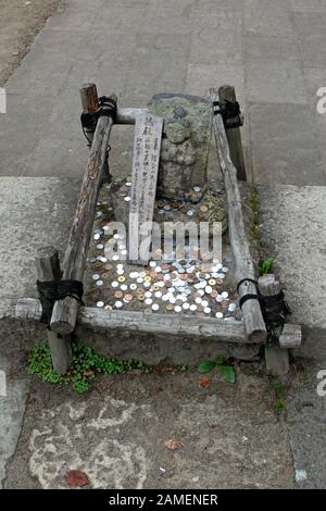 Denaro e monete gettate da persone e pellegrini al tempio di Yamadera o Yama-dera in Giappone, Asia. Edificio religioso giapponese e santuario buddista Foto Stock