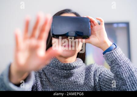 Donna che indossa occhiali per realtà virtuale. Utilizzando lo smartphone con auricolari VR Foto Stock