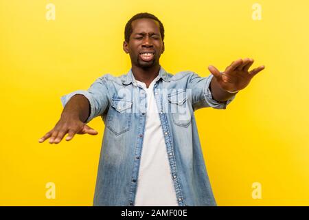 Ritratto di uomo frustrato con scarsa vista indossare denim casual camicia in piedi con occhi chiusi e mani stretching, cercando modo, concetto di cecità Foto Stock