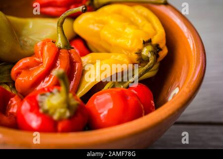 Assortimento di peperoncini caldi in un recipiente in ceramica marrone. Foto Stock