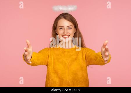 Vieni nelle mie mani! Ritratto di bella ragazza angelica zenzero con alone sopra testa braccia stretching per fotocamera con gentile sorriso amichevole, andando a embrac Foto Stock