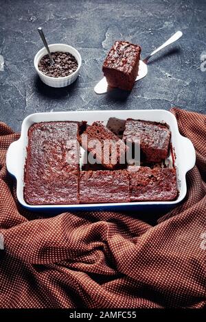 primo piano di deliziose fette di pan di spagna di cioccolato appena sfornate in un piatto da forno su un tavolo in cemento Foto Stock