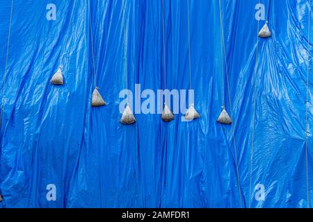 Telo protettivo impermeabile in plastica blu fissato e appesantito con  sacchi di sabbia nel cantiere, Kanazawa, Giappone Foto stock - Alamy