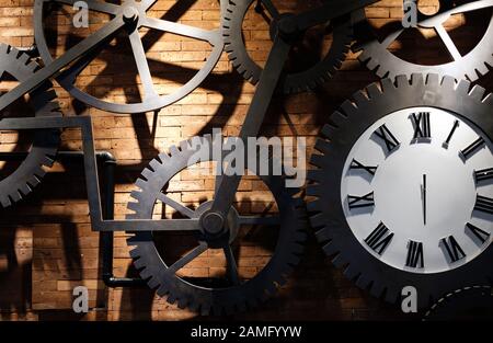 Orologio su un muro di mattoni rossi con ingranaggi di coss Foto Stock