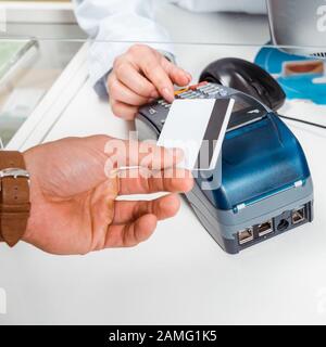 Vista ritagliata dell'uomo che paga con paypass in farmacia Foto Stock