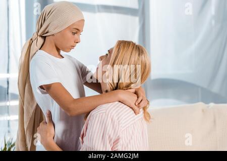 bambino malato in sciarpa della testa che abbraccia la madre a casa Foto Stock