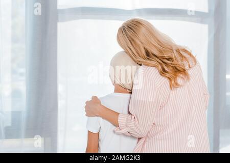 vista posteriore della madre che abbraccia la figlia nella sciarpa della testa Foto Stock
