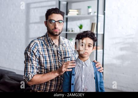 il padre ebreo abbraccia il figlio e guarda la macchina fotografica in appartamento Foto Stock