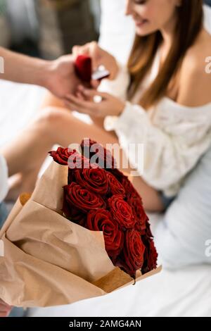 vista corta dell'uomo con bouquet che fa la proposta di matrimonio a donna sorridente Foto Stock