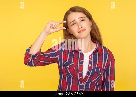 Così piccolo! Ritratto di una ragazza di zenzero deluso ma positivo in camicia che mostra un po 'di gesto e smirking alla fotocamera, dimensione di misurazione, bisogno di più. Io Foto Stock