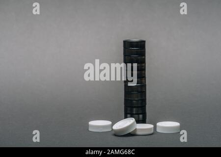 Pedine in bianco e nero su sfondo grigio con spazio di copia Foto Stock