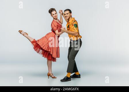 ballerini sorridenti che tengono le mani mentre ballano boogie-woogie su sfondo grigio Foto Stock