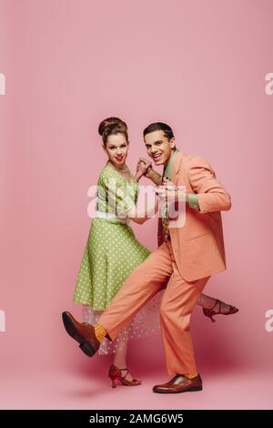 ballerini giovani che tengono le mani mentre ballano boogie-woogie su sfondo rosa Foto Stock