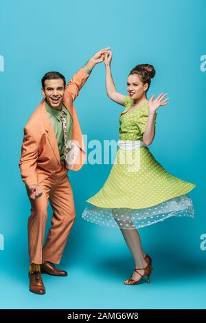 ballerini eleganti che tengono le mani mentre ballano boogie-woogie su sfondo blu Foto Stock
